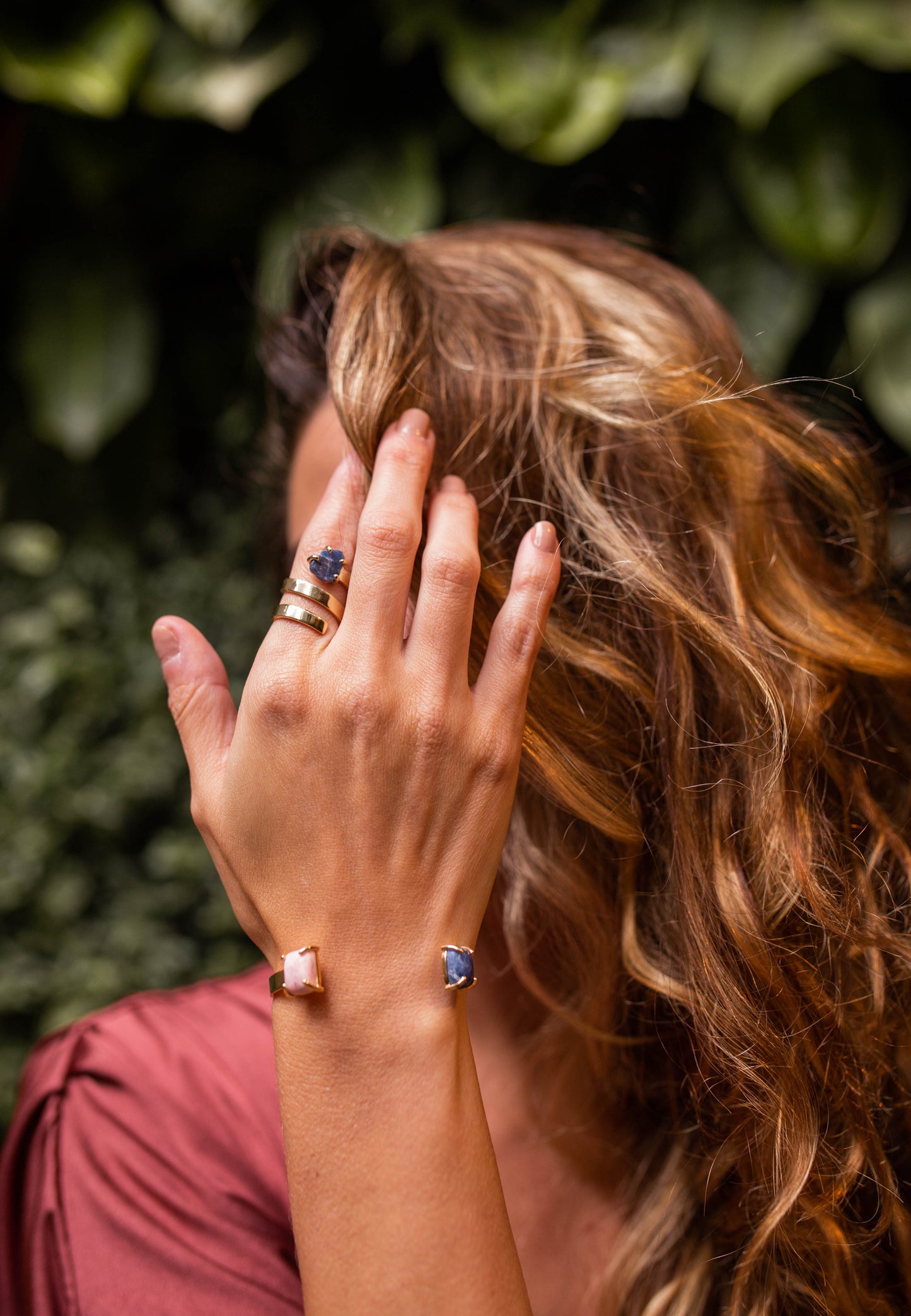 Mulher com a mão no rosto usando o anel Ruta 40 em ouro 18k com pedra Sodalita. 